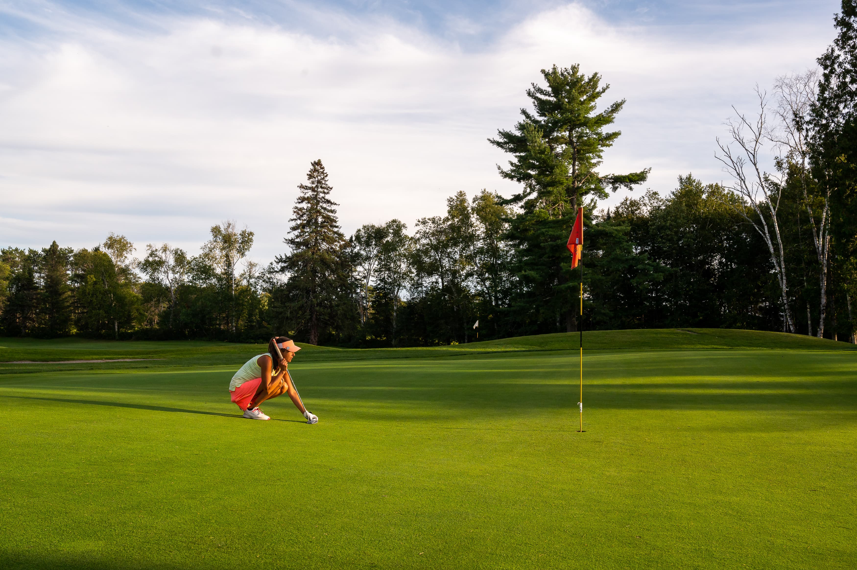 Un golfeur lit sa ligne de coup roulé sur le vert du Golf Arundel.